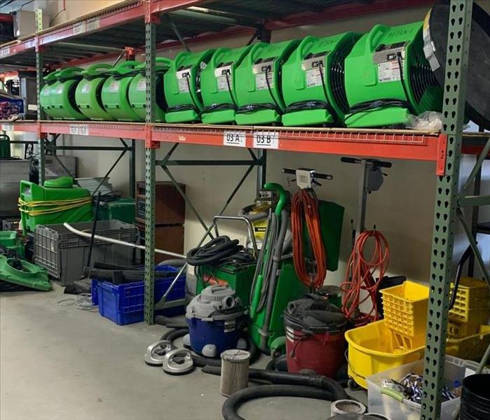 SERVPRO equipment on shelves and the floor of a garage. 