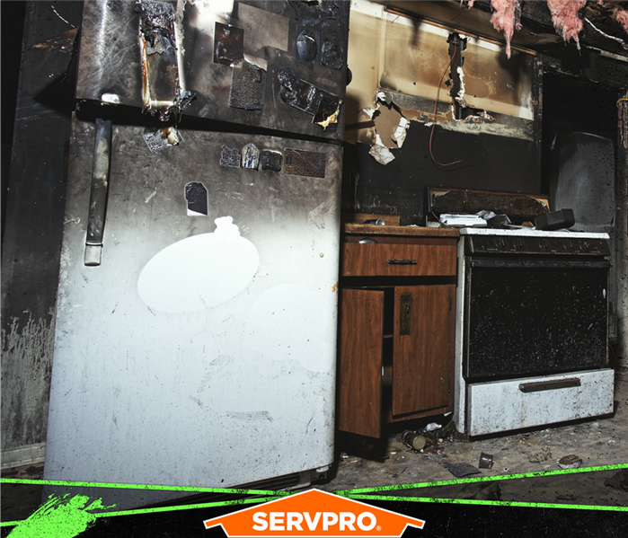 Fire damage to kitchen with soot on fridge and insulation hanging from the ceiling.